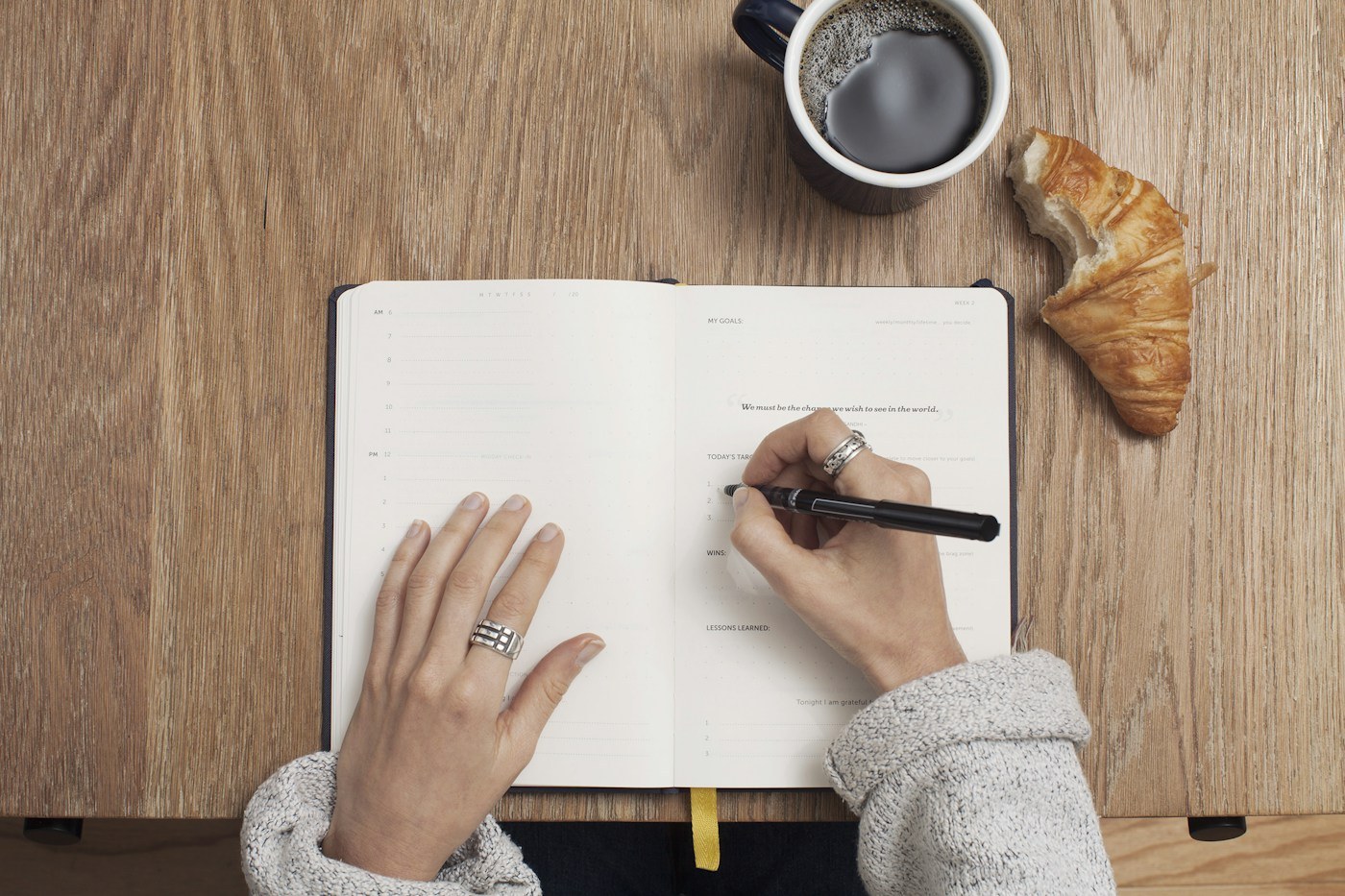 An open notebook on a table beside coffee